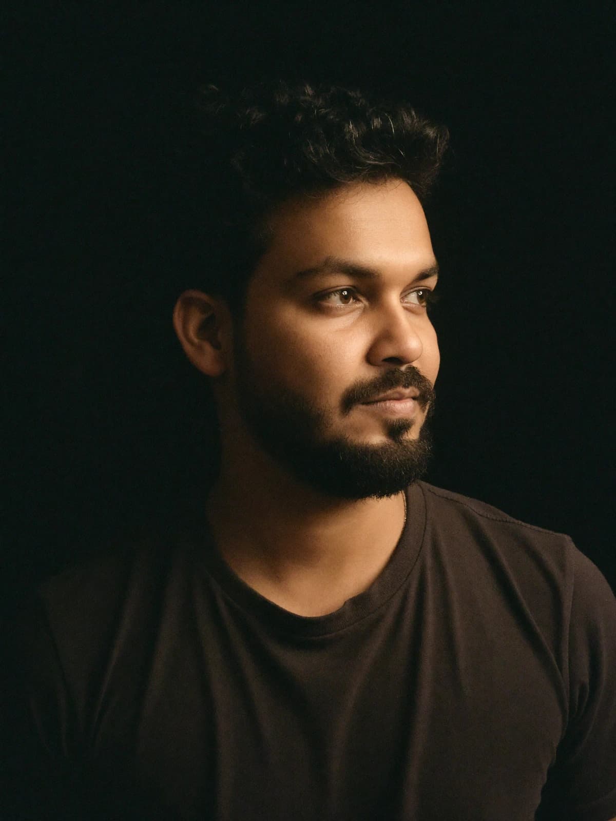 Sankar looking away from the camera in low amber light
